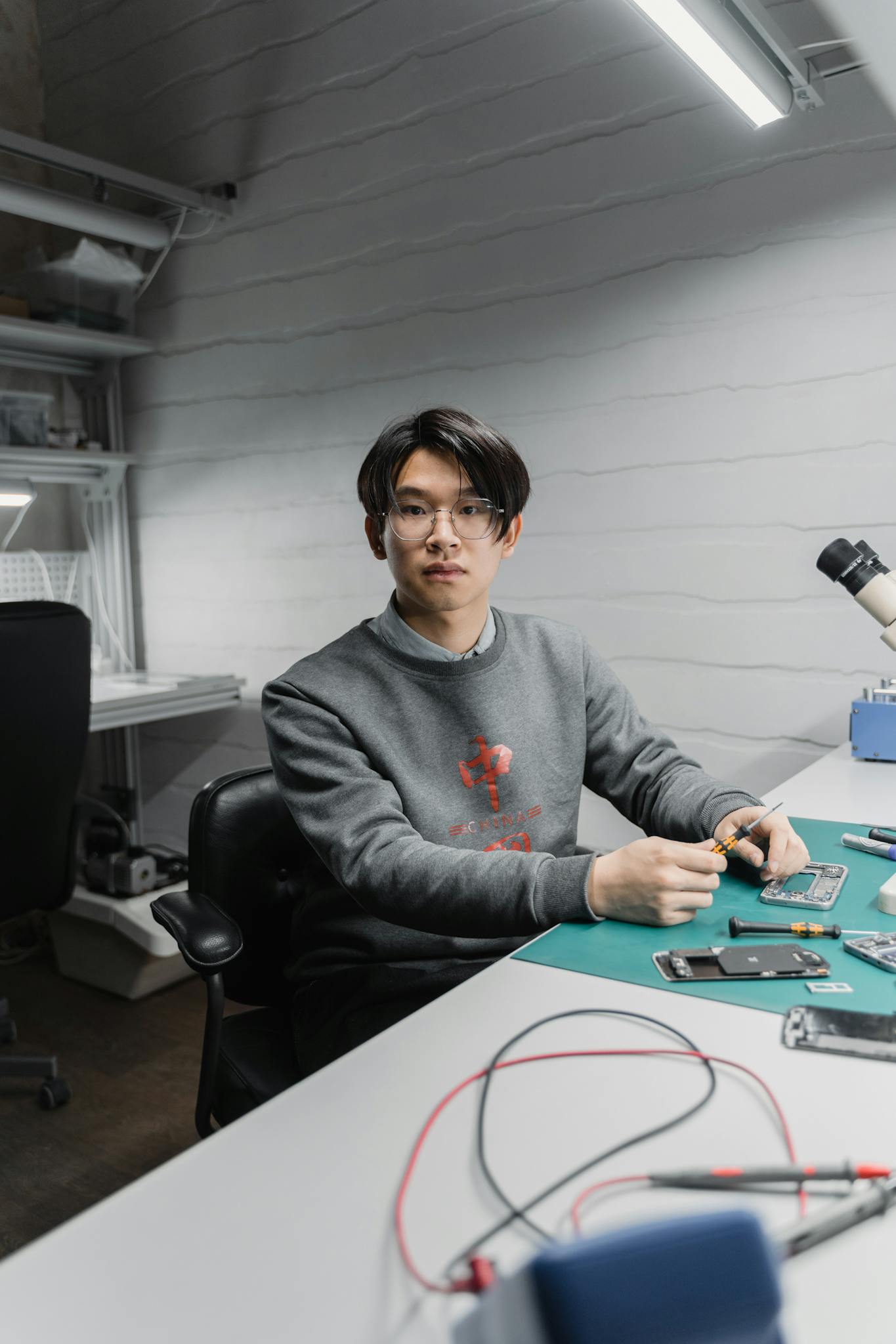 Focused young man working on electronic devices in a modern workspace.